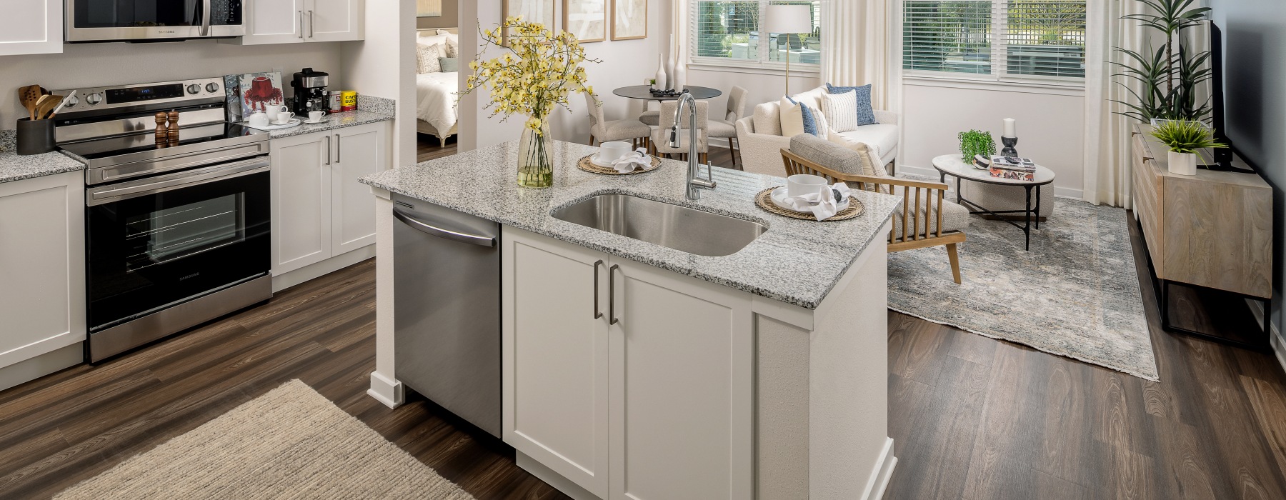Luxury Apartments in Kissimmee, FL, with In-Unit Washer and Dryer - Cielo View - Kitchen with Granite Countertops, Stainless Steel Appliances, Double Sink, and White Cabinets Opening to Living Area.