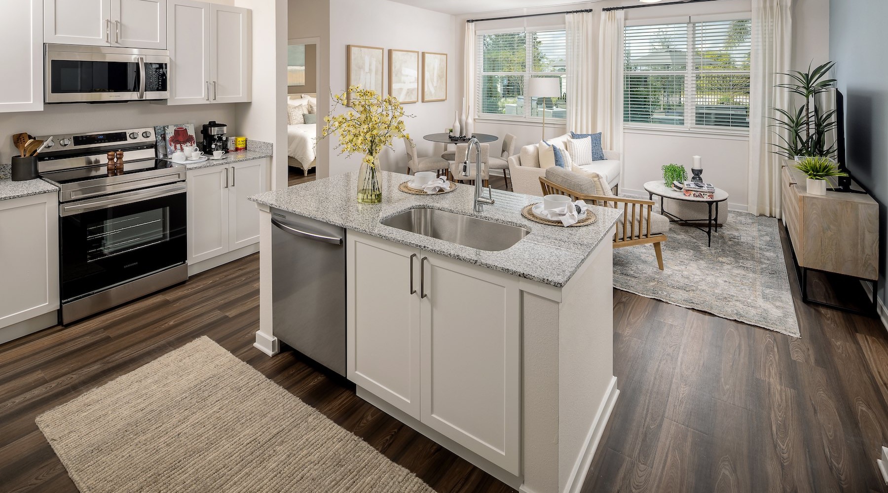 Luxury Apartments in Kissimmee, FL, with In-Unit Washer and Dryer - Cielo View - Kitchen with Granite Countertops, Stainless Steel Appliances, Double Sink, and White Cabinets Opening to Living Area.